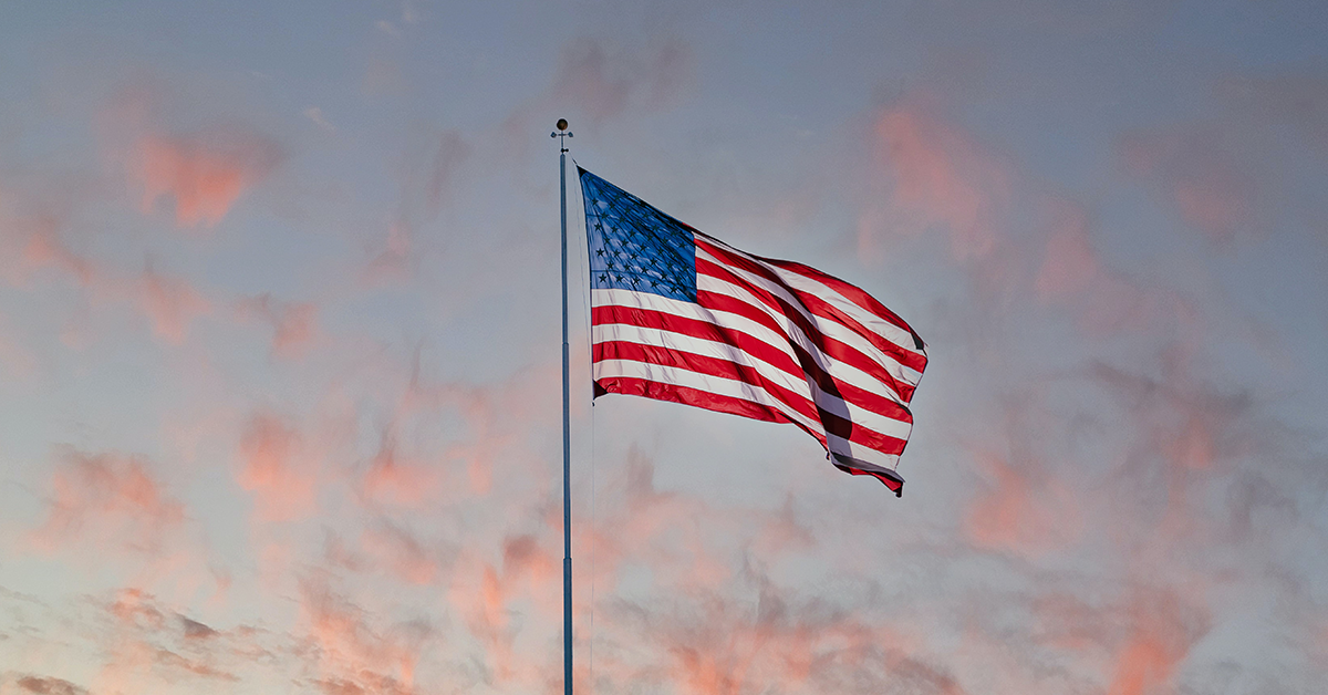 10 Steps You Can Take Now To Prepare You for Citizenship in the US, image of an American flag waving in the air with a sunset