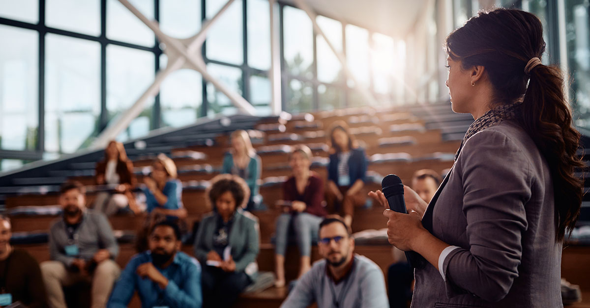 Understanding-EB-1A-Eligibility--Criteria-and-Examples, image of a immigrant woman giving a speech.